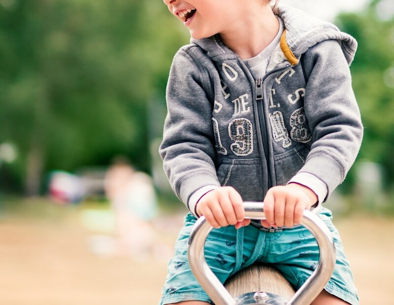 baby in blue denim jacket sitting on brown wooden chair during daytime